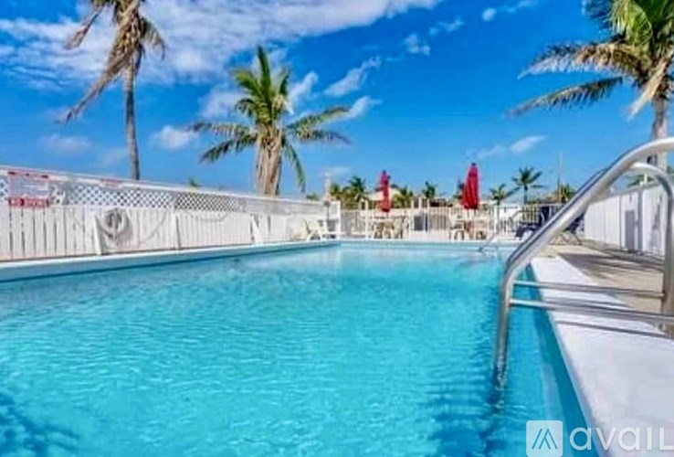 A pool surrounded by palm trees and red umbrellas.