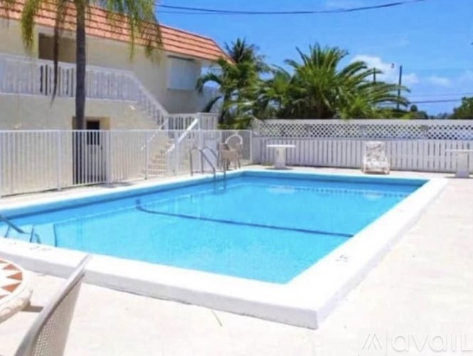 A small pool with a white fence and a house in the background.