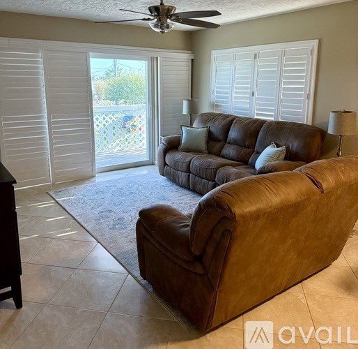 A brown leather couch in a room with a ceiling fan.