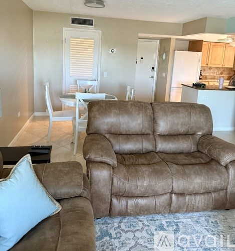 A brown recliner sofa is in the foreground of a living room.