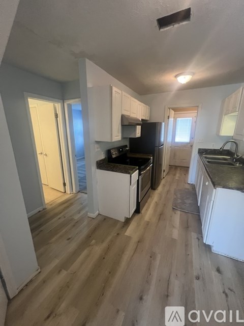 A kitchen with white cabinets and a black countertop.