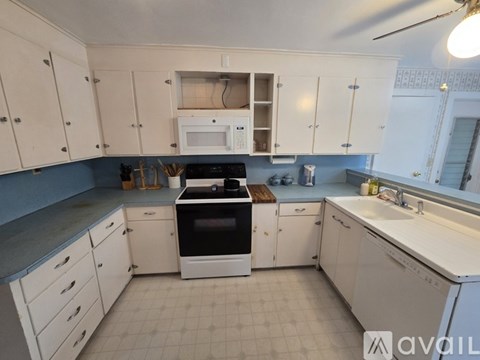 A kitchen with white cabinets and a black stove top oven.