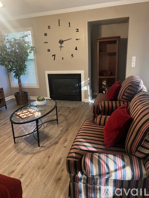 A living room with a striped couch and a large clock on the wall.