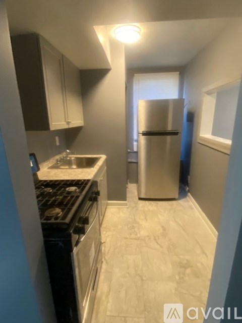 A kitchen with a stove, sink, and refrigerator.