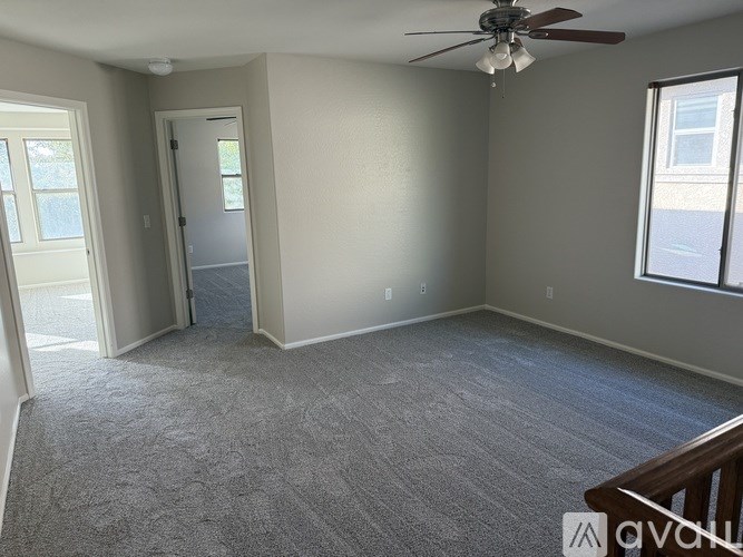 A room with a ceiling fan and carpeted floor.