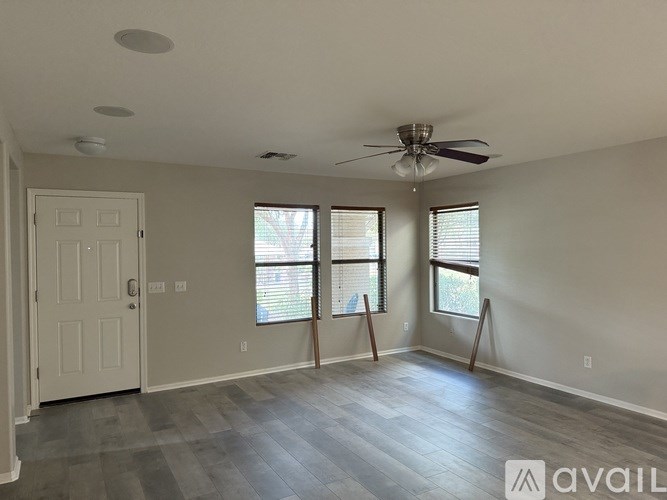 A room with a ceiling fan and two windows.