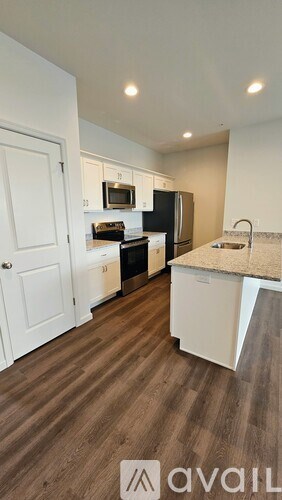 A kitchen with white cabinets and a wooden floor.