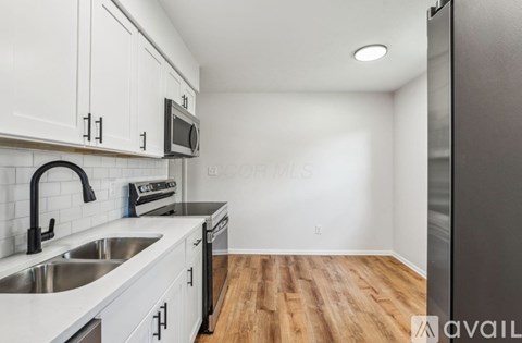 A kitchen with white cabinets and a black refrigerator.