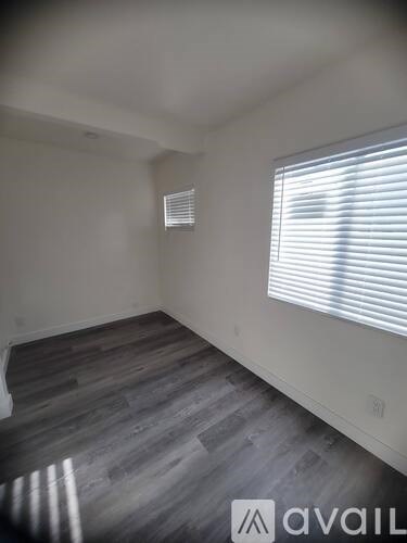 A room with wooden flooring and a window with blinds.