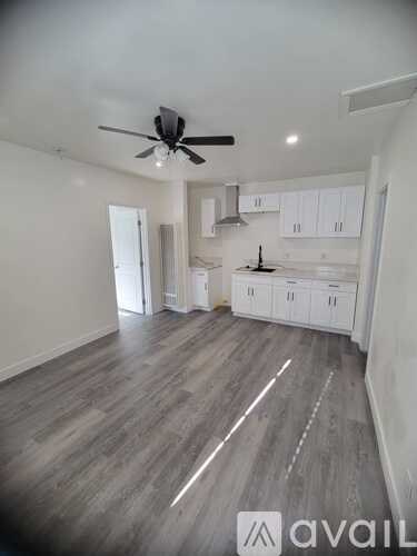 A spacious room with a ceiling fan and wooden flooring.