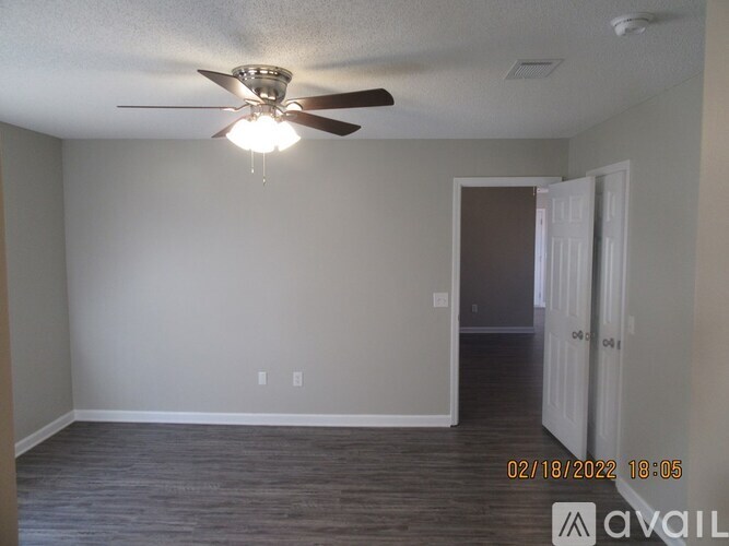 A room with a ceiling fan and light fixture, and a door on the right.