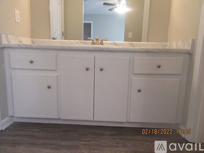 A bathroom vanity with a marble top and white cabinets.