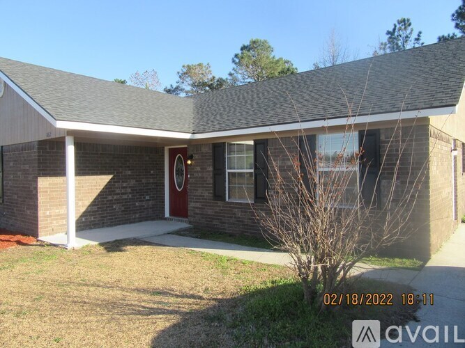 A house with a red door and a tree in front.