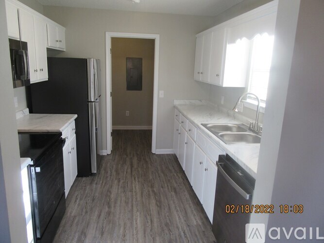 A kitchen with black appliances and white cabinets.