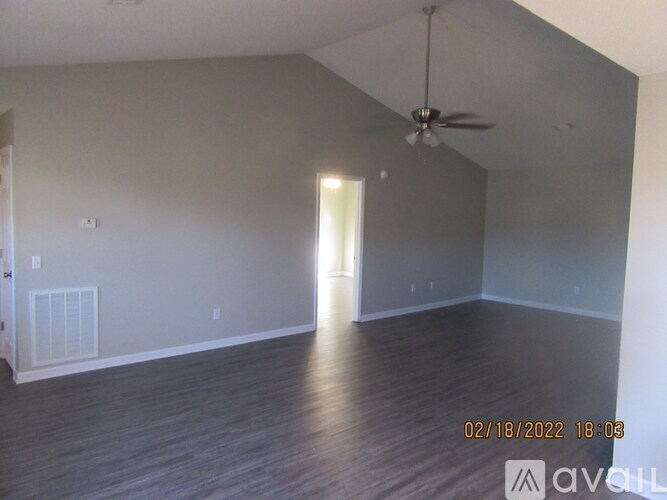 A room with a ceiling fan and wooden flooring.
