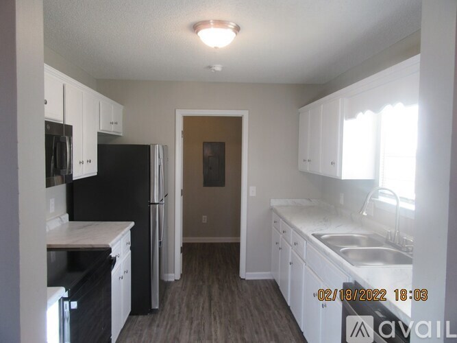 A kitchen with white cabinets and a black refrigerator.