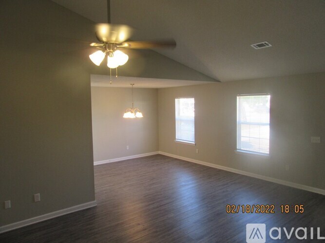 A room with a ceiling fan and two windows.