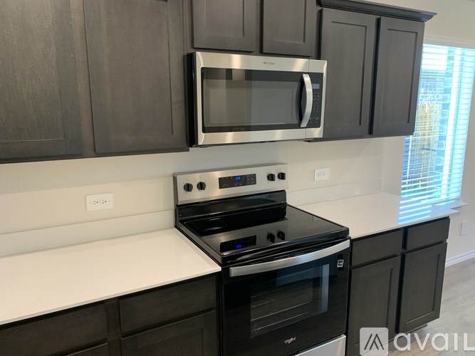 A kitchen with a black stove and microwave above it.