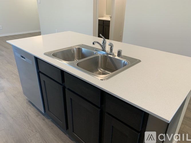 A kitchen with a white countertop and a stainless steel sink.
