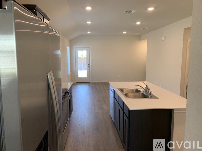 A modern kitchen with a stainless steel refrigerator and wooden flooring.