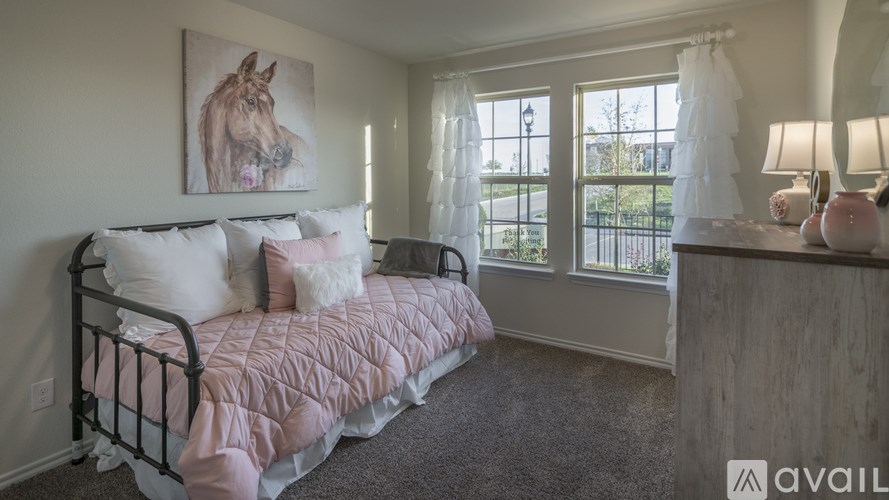 A bedroom with a pink bedspread and a painting of a horse on the wall.
