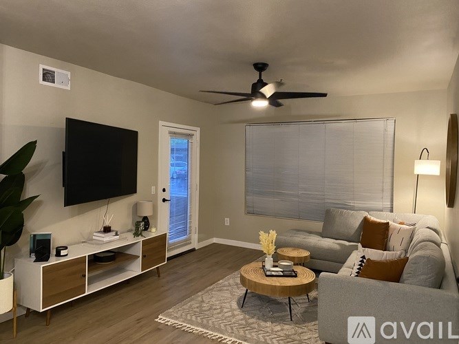 A living room with a grey couch, a wooden coffee table, and a flat screen TV mounted on the wall.