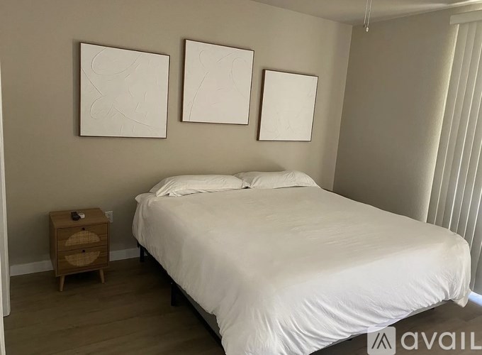 A bedroom with a white bed and two empty picture frames on the wall.