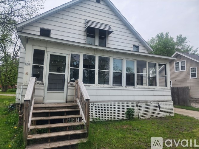A house with a white exterior and a grey roof with a small window on the roof.