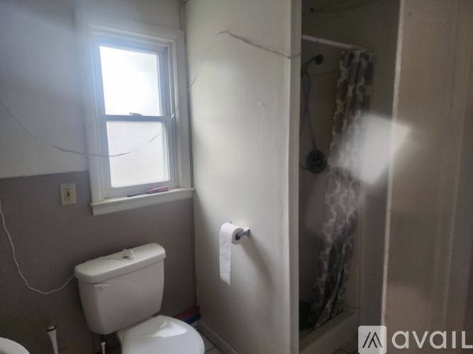 A bathroom with a toilet, a window, and a shower.