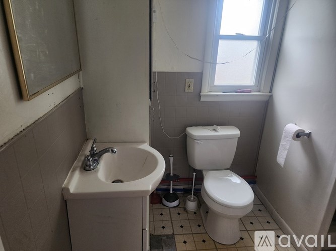 A bathroom with a toilet, sink, and window.