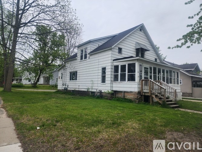 A white house with a grey roof and a porch.