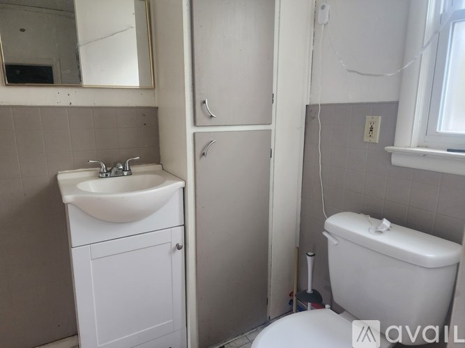 A bathroom with a sink, toilet, and a mirror.