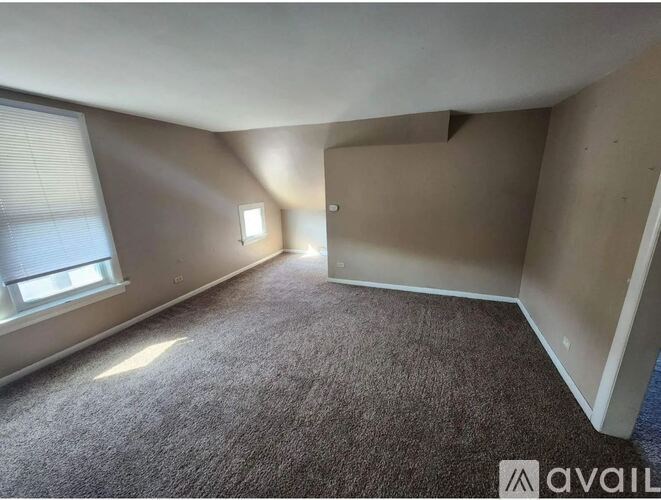 A room with carpeted floor and a window with blinds.