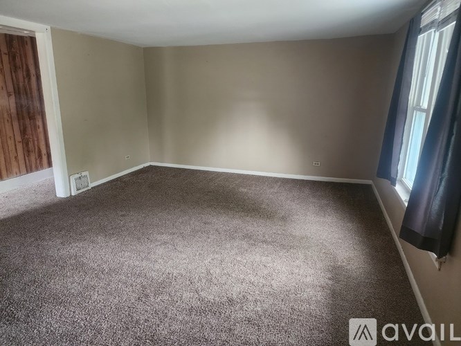 A room with a carpeted floor and a window with curtains.