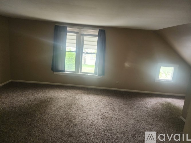 A room with a carpeted floor and a window with curtains.