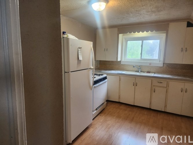 A kitchen with a white refrigerator and wooden floors.