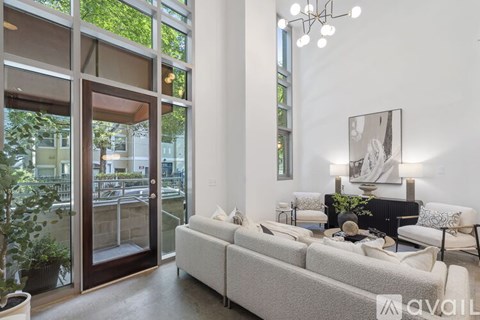 A living room with a couch, a chair, a potted plant, and a painting on the wall.