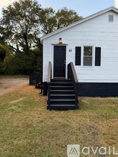 A white house with a black door and steps leading up to it.