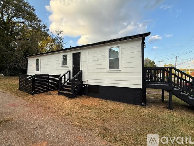 A white mobile home with a black front porch.