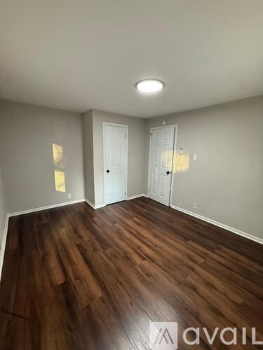 A room with wooden floors and two white doors.
