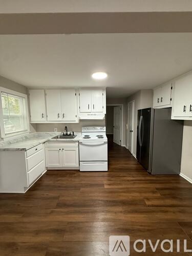 A kitchen with white cabinets and a wooden floor.