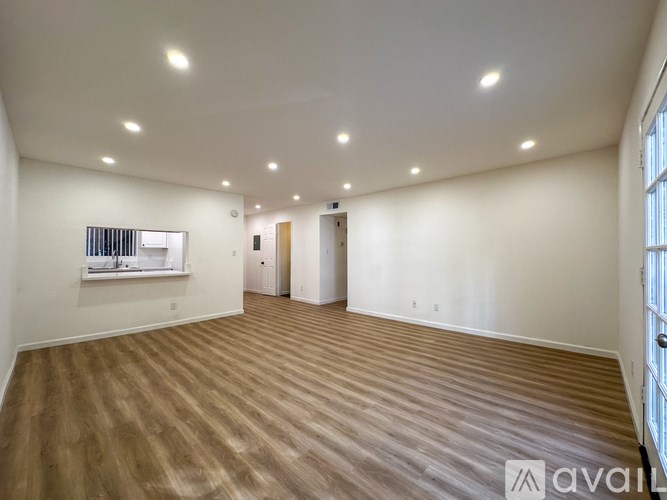 A spacious room with wooden flooring and white walls.