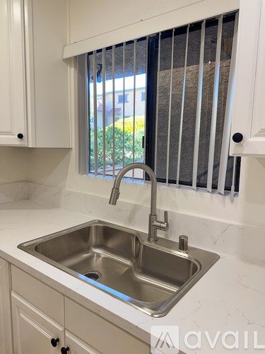 A kitchen sink with a chrome faucet and a window above it.