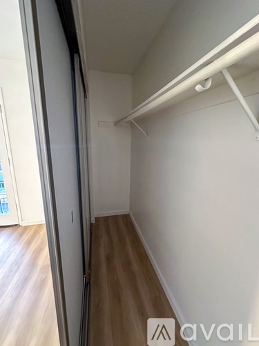 A long white hallway with a white door on the left and a white wall on the right.