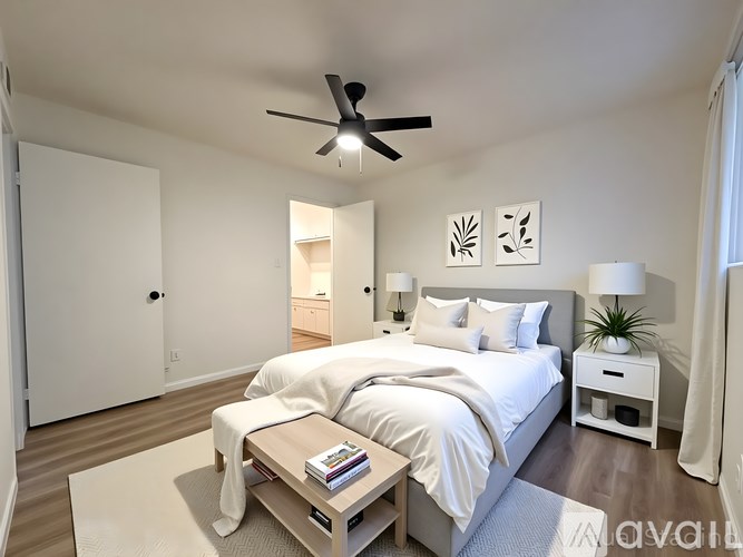 A bedroom with a large bed, a ceiling fan, and a nightstand with a plant on it.