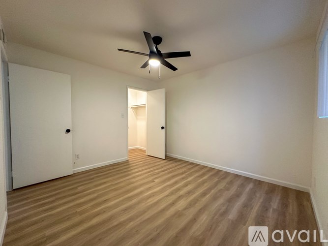 A room with a ceiling fan and wooden flooring.