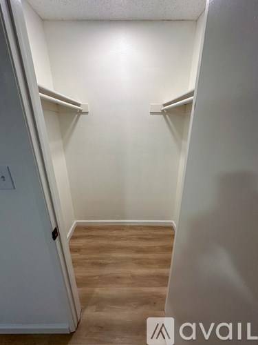 A small, empty room with a door on the left and a shelf on the right.