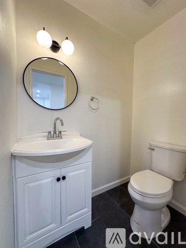 A white bathroom with a toilet, sink and mirror.