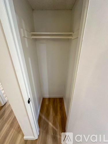 A small, empty room with a wooden floor and white walls.