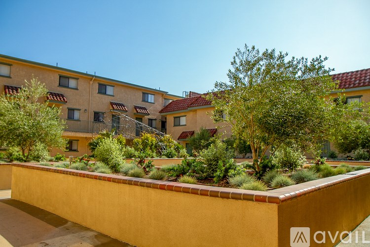 A building with a red roof and a courtyard with trees and bushes.